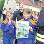 Kinder der Jugendfeuerwehr präsentieren den Flyer zum Geocaching der bunten Pfähle